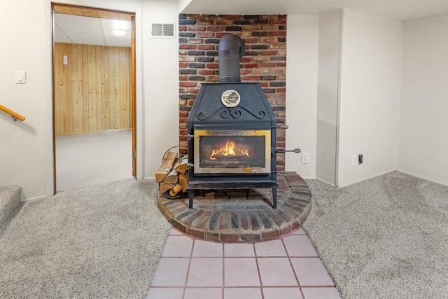 room details featuring carpet floors, wooden walls, and a wood stove