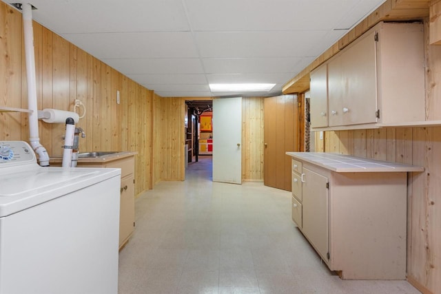 laundry area with washer / clothes dryer, sink, cabinets, and wood walls