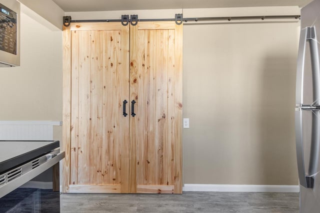 kitchen with dark wood-type flooring, light brown cabinetry, and stainless steel refrigerator