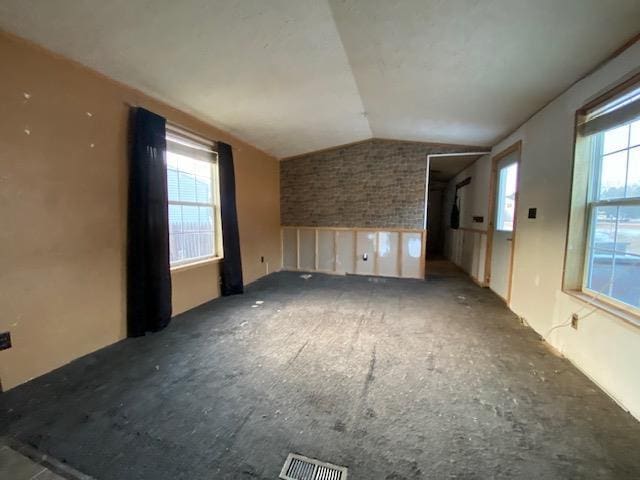 unfurnished room with lofted ceiling and plenty of natural light