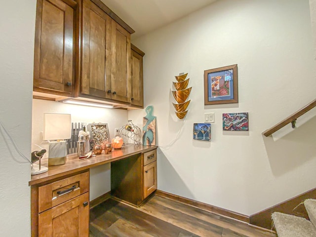 bar with dark hardwood / wood-style floors and built in desk