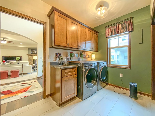 laundry room with sink, cabinets, washer and dryer, ceiling fan, and a fireplace