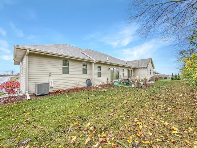 rear view of property with cooling unit, a patio, and a lawn