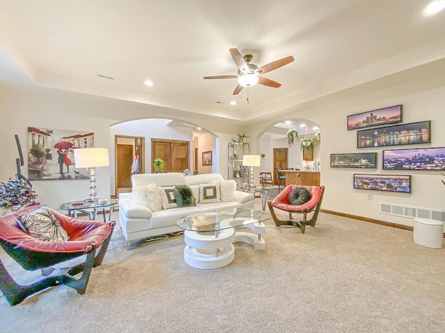 living room featuring ceiling fan, carpet flooring, and a raised ceiling