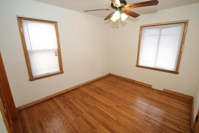 spare room featuring ceiling fan, wood-type flooring, and plenty of natural light