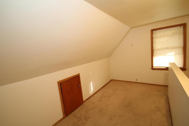 bonus room with vaulted ceiling and light carpet