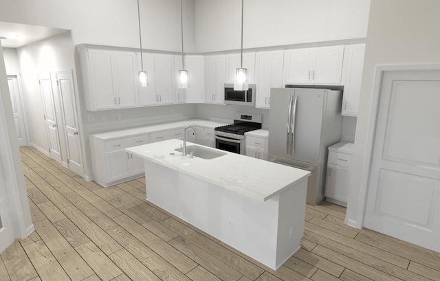 kitchen with appliances with stainless steel finishes, pendant lighting, white cabinetry, sink, and a kitchen island with sink