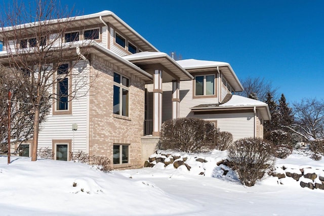 view of snow covered exterior with brick siding