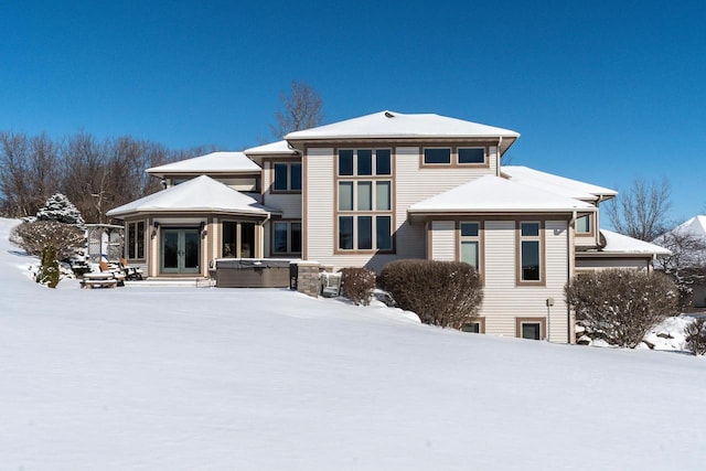 snow covered back of property with french doors, a hot tub, and a gazebo