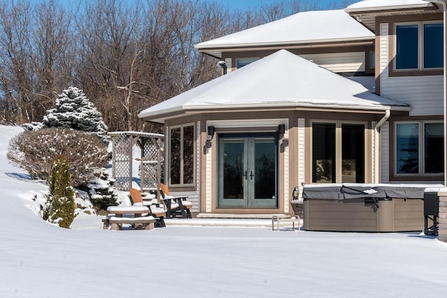 snow covered property featuring french doors and a hot tub