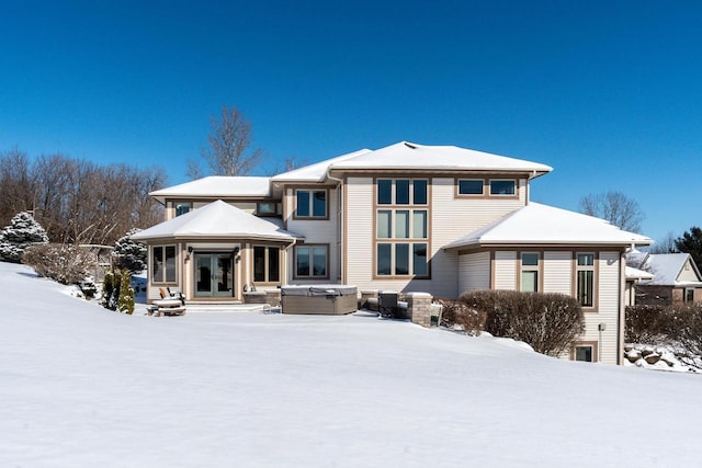 snow covered property with french doors and a hot tub