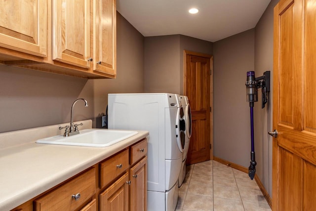 laundry area featuring light tile patterned flooring, a sink, baseboards, independent washer and dryer, and cabinet space