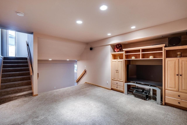 unfurnished living room featuring recessed lighting, carpet flooring, plenty of natural light, and stairway