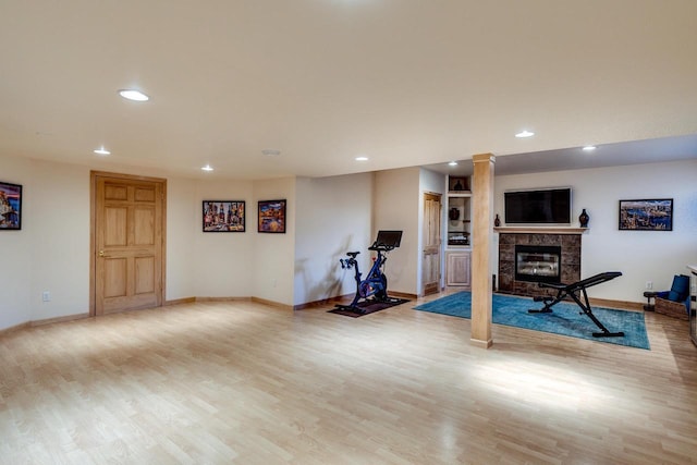 workout area featuring a high end fireplace, light wood finished floors, and recessed lighting