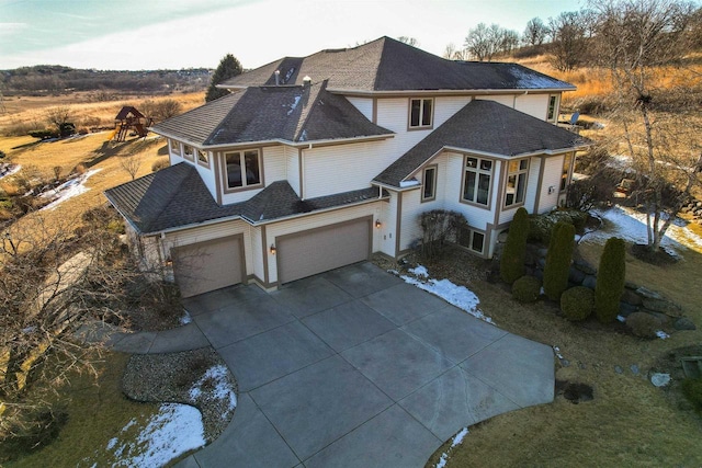 view of front of home with an attached garage, a shingled roof, and concrete driveway