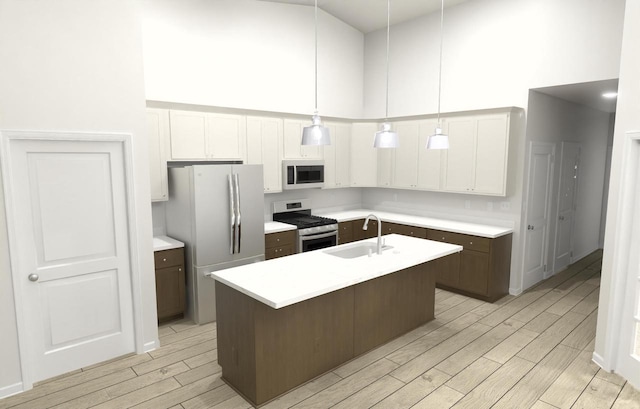 kitchen with white cabinetry, hanging light fixtures, stainless steel appliances, and an island with sink