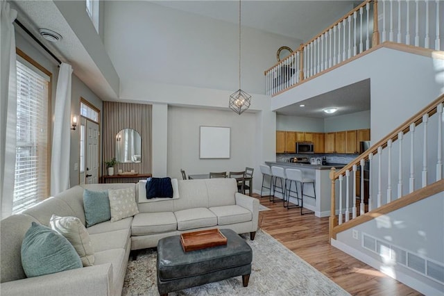 living room featuring a towering ceiling and light hardwood / wood-style flooring