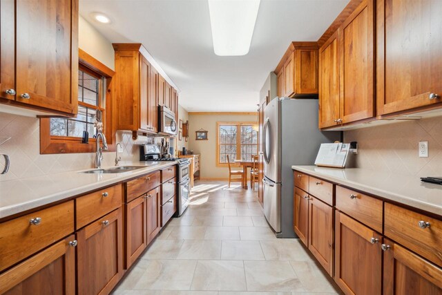 1726 Wynn Wood Ln, Harpers Ferry, IA 52146 - kitchen featuring stainless steel appliances, light countertops, brown cabinetry, and a sink