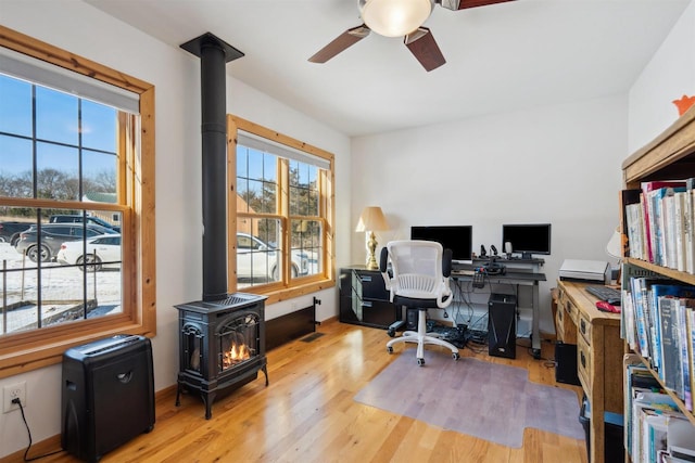 1726 Wynn Wood Ln, Harpers Ferry, IA 52146 - office area featuring a wood stove, a ceiling fan, and wood finished floors