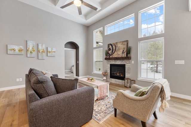 living room with a towering ceiling, a fireplace, and light hardwood / wood-style flooring