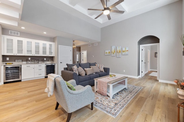 living room featuring indoor bar, beverage cooler, and a high ceiling