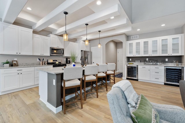 kitchen with wine cooler, stainless steel appliances, light stone countertops, and white cabinets