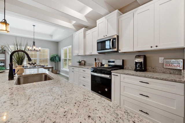 kitchen with decorative light fixtures, sink, white cabinets, light stone counters, and stainless steel appliances