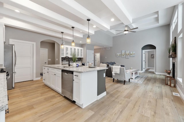 kitchen with sink, white cabinetry, hanging light fixtures, stainless steel appliances, and a center island with sink