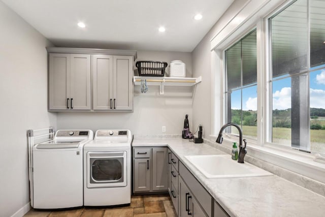 washroom with cabinets, washer and clothes dryer, and sink