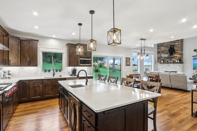 kitchen with a kitchen bar, sink, a kitchen island with sink, pendant lighting, and light hardwood / wood-style floors