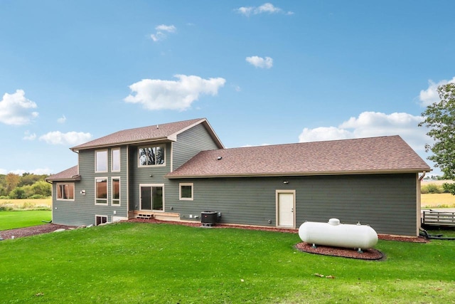 rear view of house featuring cooling unit and a lawn