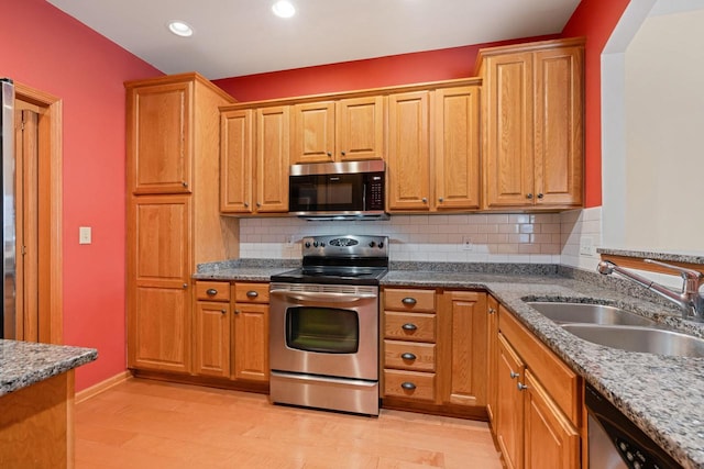 kitchen featuring stainless steel appliances, tasteful backsplash, sink, and light wood-type flooring