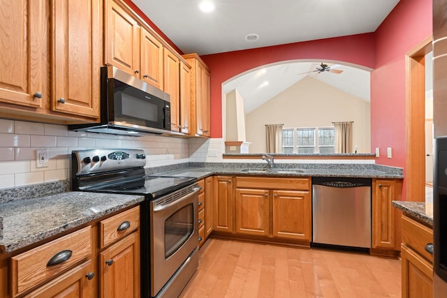 kitchen with stainless steel appliances, tasteful backsplash, sink, and dark stone counters