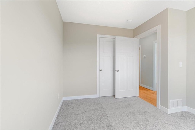 unfurnished bedroom featuring light colored carpet and a closet