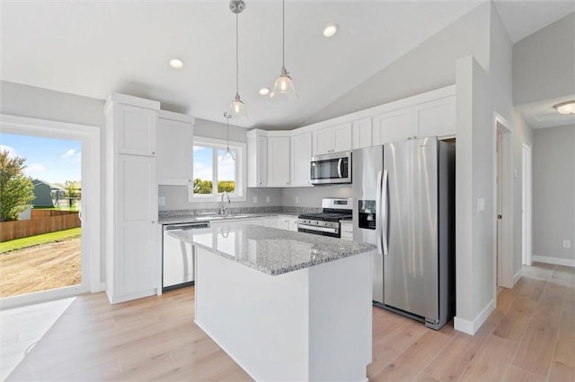 kitchen featuring decorative light fixtures, white cabinetry, a center island, stainless steel appliances, and light stone countertops