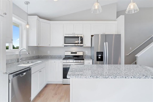 kitchen with appliances with stainless steel finishes, decorative light fixtures, white cabinetry, lofted ceiling, and sink