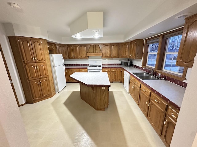 kitchen with sink, white appliances, a center island, and premium range hood