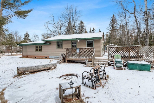 snow covered house featuring a wooden deck and a fire pit