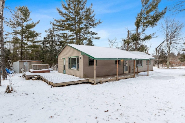 snow covered house with a wooden deck and a storage unit