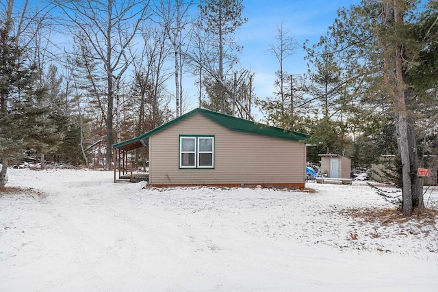 view of snow covered exterior with a storage shed