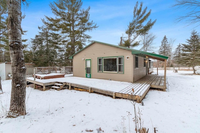 snow covered back of property with a deck