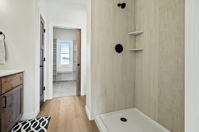 bathroom with hardwood / wood-style flooring, vanity, and tiled shower