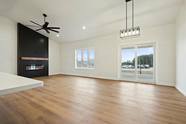 unfurnished living room with ceiling fan, a fireplace, vaulted ceiling, and light wood-type flooring