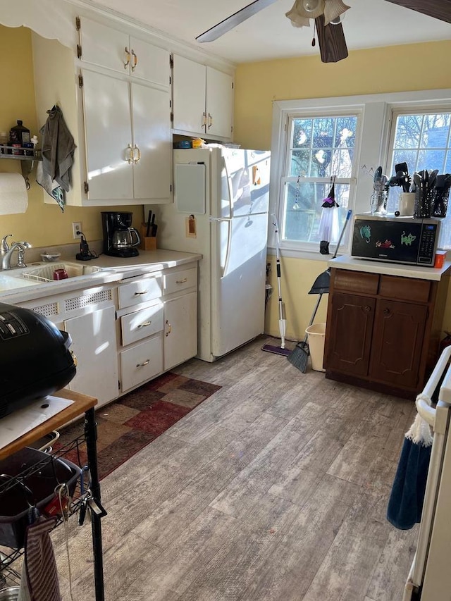 kitchen featuring a healthy amount of sunlight, sink, white fridge, and white cabinets