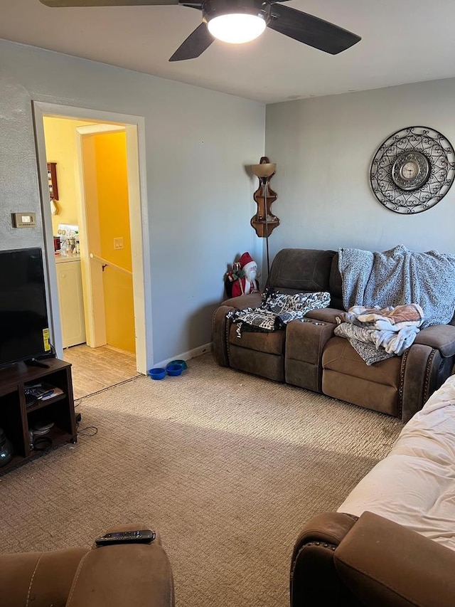 carpeted living room with ceiling fan and washer / dryer