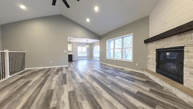 unfurnished living room with hardwood / wood-style floors, a fireplace, high vaulted ceiling, and ceiling fan