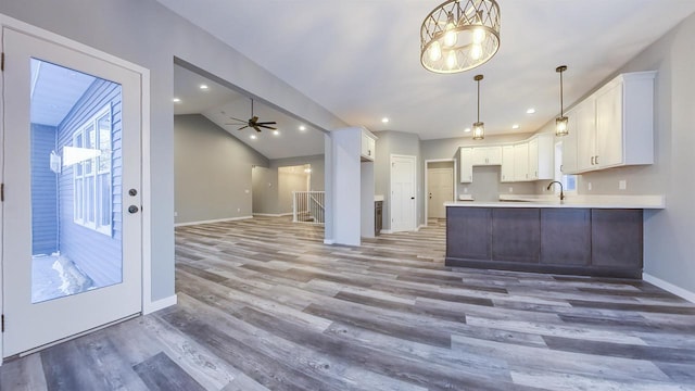 kitchen featuring lofted ceiling, sink, wood-type flooring, and white cabinets