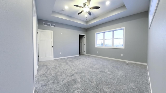 carpeted empty room with ceiling fan and a raised ceiling