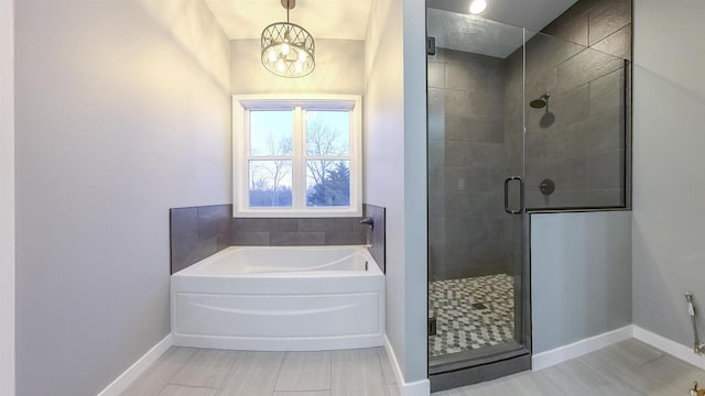 bathroom with a notable chandelier and separate shower and tub