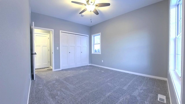 unfurnished bedroom with dark colored carpet, ceiling fan, and a closet